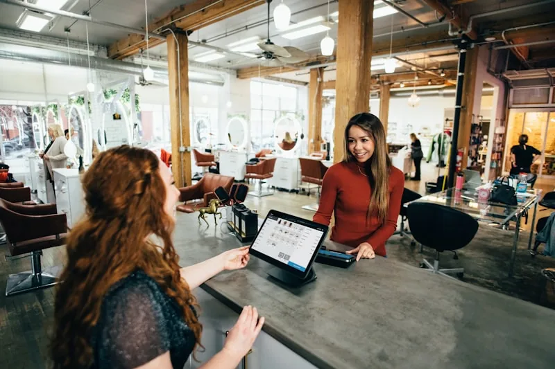 Recepcionista em salão de beleza usando tablet no balcão de atendimento