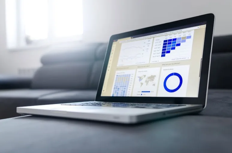 Notebook no sofá exibindo painel de analytics com mapa mundial e gráficos